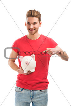 Handsome young man holding a piggy bank