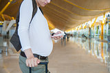 pregnant touching phone in airport