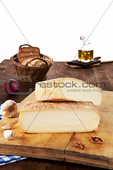Cheese pieces with bread on wooden board.