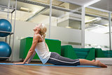 Side view of woman stretching her back in fitness studio