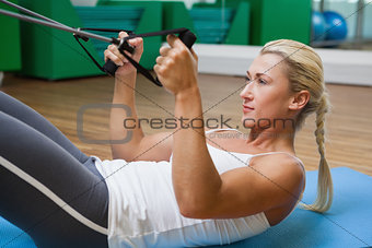 Sporty woman using resistance band in fitness studio