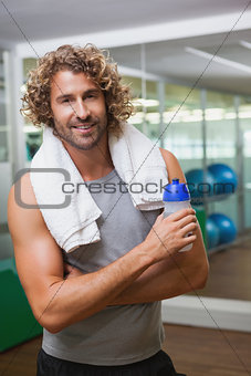Smiling handsome man holding water bottle at gym