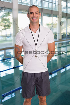 Swimming coach by pool smiling at leisure center
