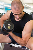 Young man exercising with dumbbell in gym