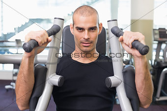 Serious man working on fitness machine at gym