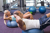 Fit couple doing abdominal crunches at gym