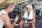 Male trainer assisting woman with dumbbell in gym