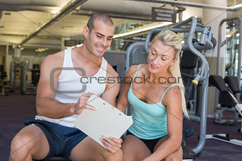 Woman discussing her performance on clipboard with trainer at gym