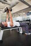 Fit man lifting dumbbell lying on the bench