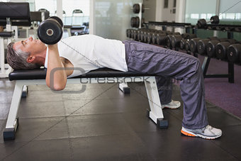 Fit man lifting dumbbells lying on the bench