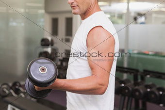 Fit man lifting heavy black dumbbell