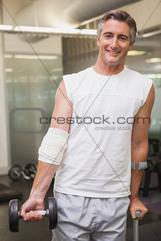Injured man holding dumbbell in the weights room