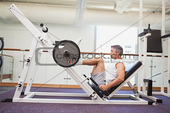 Fit man lifting heavy barbell with legs