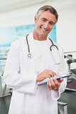Confident doctor standing in fitness studio using tablet pc