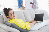 Young creative woman using laptop on couch