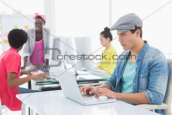 Young creative man using laptop at desk