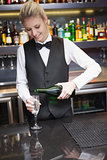 Cute woman in suit pouring champagne into flute