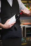 Handsome waiter opening a bottle of red wine