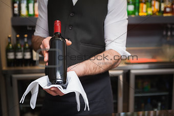 Handsome waiter holding a bottle of red wine