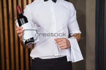Handsome waiter holding a bottle of red wine and a towel