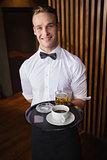 Smiling waiter holding tray with coffee cup and pint of beer