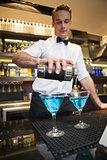 Bartender pouring cocktail into glasses
