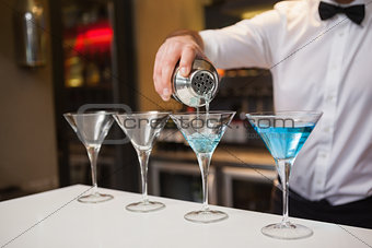 Bartender pouring blue alcohol into cocktail glass