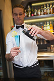Handsome bartender serving blue cocktail