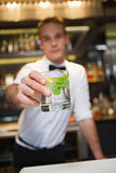 Happy bartender offering cocktail to camera