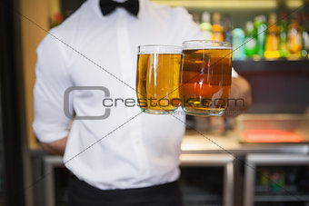 Bartender holding two glasses of beer