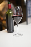 Close up of red wine into glass in front of the bottle