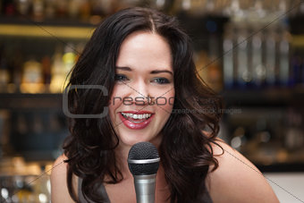 Happy brunette singing into mic