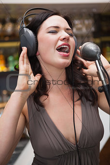 Woman singing with her hands on her headphone