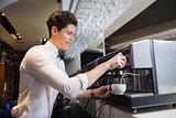 Smiling young barista making cup of coffee