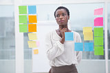 Creative businesswoman looking at sticky notes on window