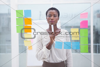 Thoughtful businesswoman holding a marker