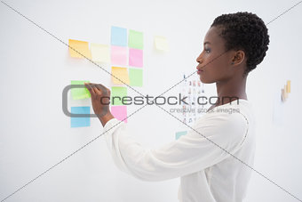 Pretty designer looking at sticky notes on window