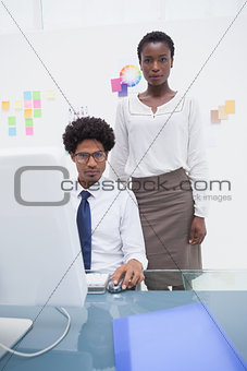 Coworkers using computer and looking at camera
