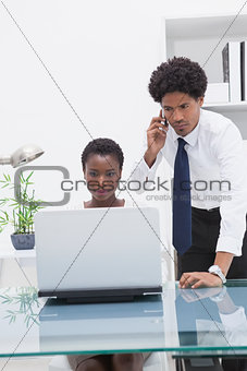 Concentrated colleagues using laptop and phoning