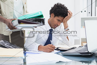 Woman giving pile of ring binders to her exhausted colleague