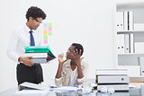 Man giving pile of files to his irritated colleague
