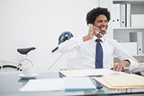 Smiling businessman on the phone at desk