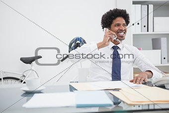 Smiling businessman on the phone at desk