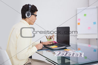 Businessman enjoying music and using laptop