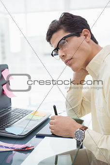 Designer with glasses thinking and using digitizer