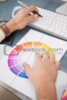 Designer using a colour wheel and typing on keyboard