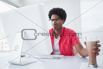 Concentrated businessman with milkshake using computer