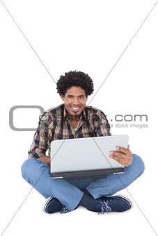 Smiling man sitting and using laptop