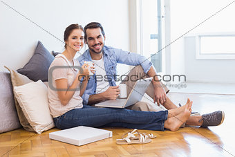 Cute couple sitting on floor using laptop