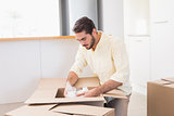 Young man unpacking boxes in kitchen